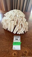 Full view of white coral statue on table with size tag
