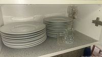 Stacks of white dinner and side plates with glasses