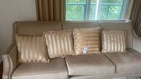 Four matching striped fringe pillows on beige sofa