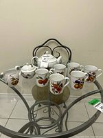 Full view of teapot, sugar, creamer and six mugs on table