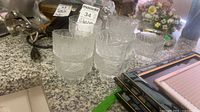 Nine matching textured clear glass compote glasses stacked on countertop