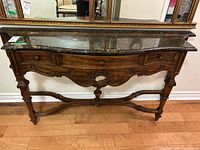Front view of console table showing drawers and carved base