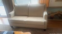 Front view of beige upholstered love seat with two seat and back cushions