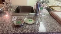 Glass vase, pewter coasters and plate on countertop