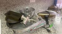 Group view of pizzelle maker, grinder and nested baking pans on countertop
