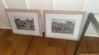 Both framed prints leaning against wall showing full view