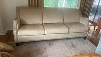 Front view of beige three-seat sofa with brass nailhead trim