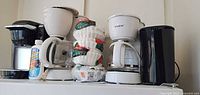 Group view of three coffee makers, kettle, filters, cleaner and carafe