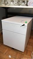 Front angle of white metal two-drawer filing cabinet on casters