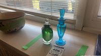Both perfume bottles on windowsill showing size and colors