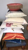 Stack of seven assorted pillows showing variety in colours and trims