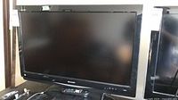 Front view of Sharp 32-inch TV on stand with remote