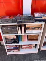 Full bookcase showing magazines on top and three shelves of assorted books