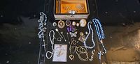 Overview of all jewelry pieces laid out including rosaries, brooches, necklaces, rings, bracelet, stickpins and earrings