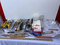 Overview of utensils, clear trays, bowls, pitcher, napkins and small tools laid on table