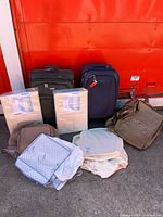 Front view showing two rolling suitcases, two packaged hanging organizers and assorted garment bags