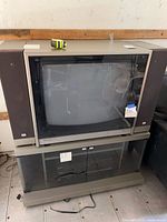 Front view of NEC CRT TV with side speakers on AV cabinet