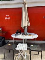 All furniture pieces: round folding table with umbrella, two glass side tables, small white folding side table