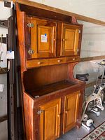 Front view of two-tone wooden kitchen hutch showing upper cabinet doors, three drawers, work surface, lower cabinet doors