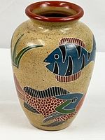 Full front view of ceramic vase showing fish motif on speckled tan background