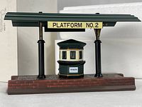 Front view of porcelain train platform showing ticket booth, pillars, roof, Platform No.2 sign