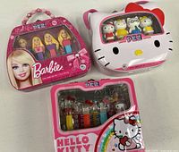 Group shot of three metal PEZ tins: Barbie, Hello Kitty cat-shaped, Hello Kitty square