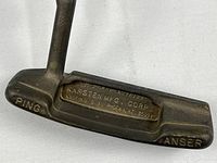 Close-up of putter head showing Ping Anser branding and bronze finish