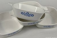 Stacked view showing all four white petite pans with blue cornflower design and side handles