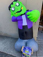 Inflated Frankenstein figure leaning against wall with box at base