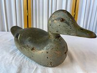 Profile of carved wooden mallard decoy showing painted surface, head, glass eye