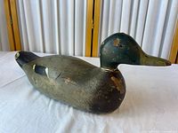 Left side view of wooden duck decoy showing head, body shape and paint wear
