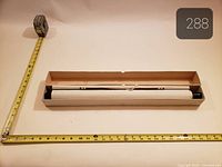 Boxed scroll with tape measure showing length and width of box