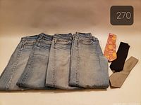 Four folded Levi’s jeans and three ties laid out