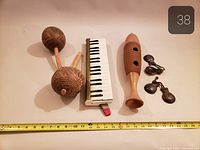 Group shot showing melodica, two maracas, guiro, pair castanets with measuring tape for scale