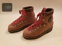 Side view of both boots displaying suede uppers, red laces, hardware, overall condition