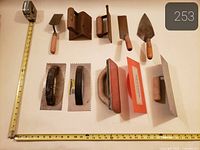 All ten tiling hand tools arranged within measuring tapes for scale