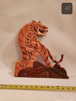 Front view of carved wooden tiger plaque with measuring tape indicating dimensions