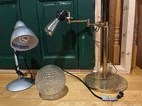 Overall view of brass table lamp, silver desk lamp, and glass globe