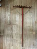 Full view of handmade wooden hay rake showing entire length, head, handle and wire braces