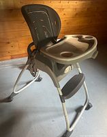 Three-quarter front view showing tray, seat shell, legs and wheels