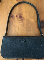 Front view of grey felt Kate Spade baguette with strap