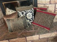 Group of seven pillows on hearth showing variety of colours and patterns