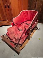 Side front view showing wood base, red padded liner, Pelican leg cover, metal supports