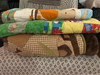 Stacked view of the three folded quilts showing colours and thickness
