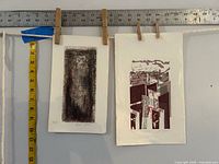 Both prints pegged under rulers displaying size reference