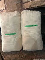 Full view of two off-white rectangular yoga bolsters leaning against stone surface