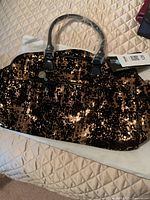 Black and copper sequined weekender bag with protective handle wrap and tag