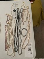 All 12 cultured pearl strands laid out on table