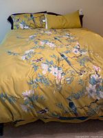 Bedding assembled on bed showing yellow bird print duvet and pillows