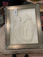 Framed white bas relief sculpture with protective wrap